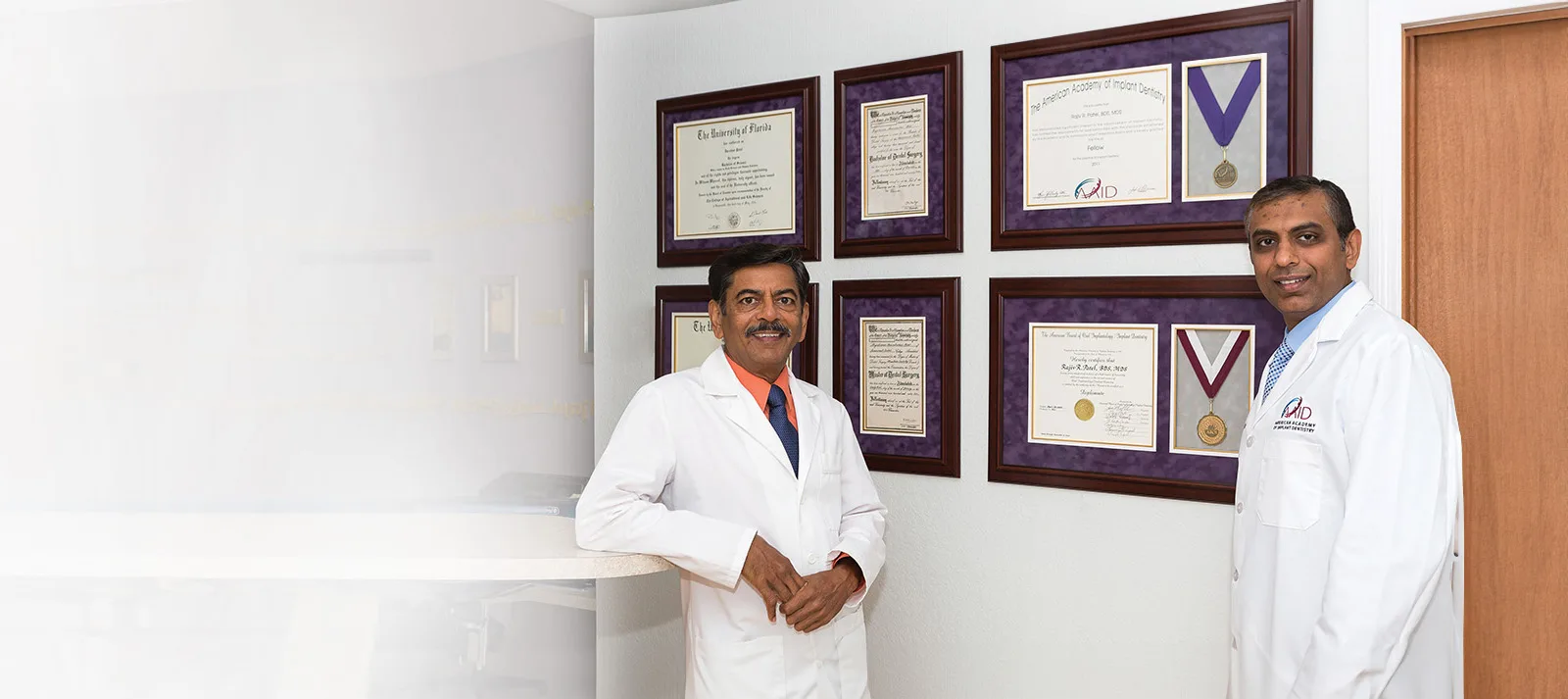 Dr. Patel with his framed dental implant credentials and awards